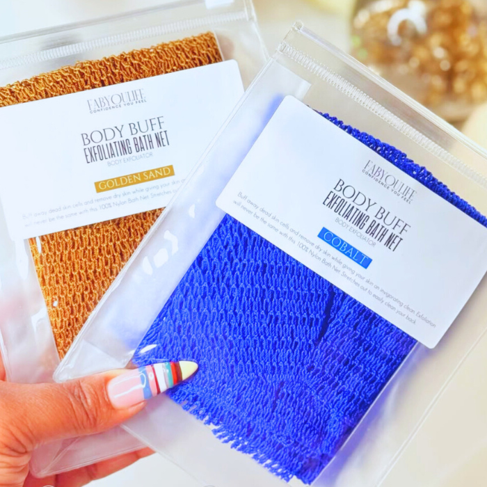 Two body buff exfoliating bath nets, one orange and one blue, held by a hand with colorful nail polish.