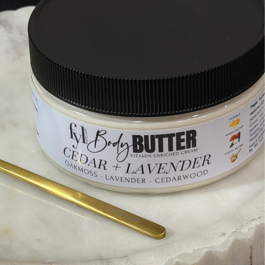 Cedar and Lavender whipped body butter by Fabyoulife in a glass jar on white marble with a gold butta spoon. Vitamin E enriched, handcrafted in Newark NJ.