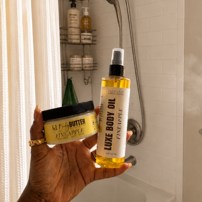 Woman holding Fineapple body butter and luxe body oil beside a shower with a green African net sponge.