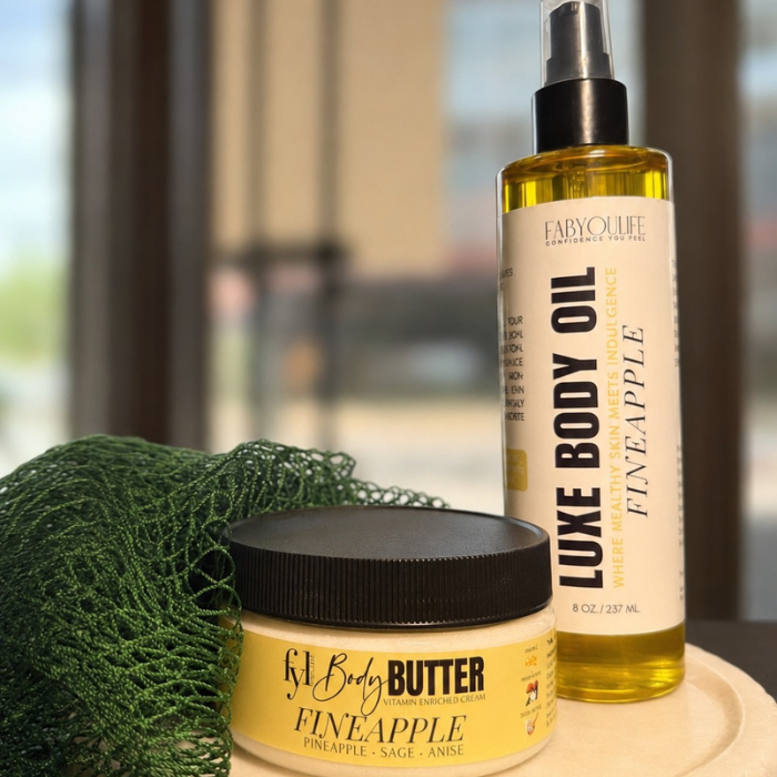 Fineapple body butter, luxe body oil and green African net sponge displayed on a tray.